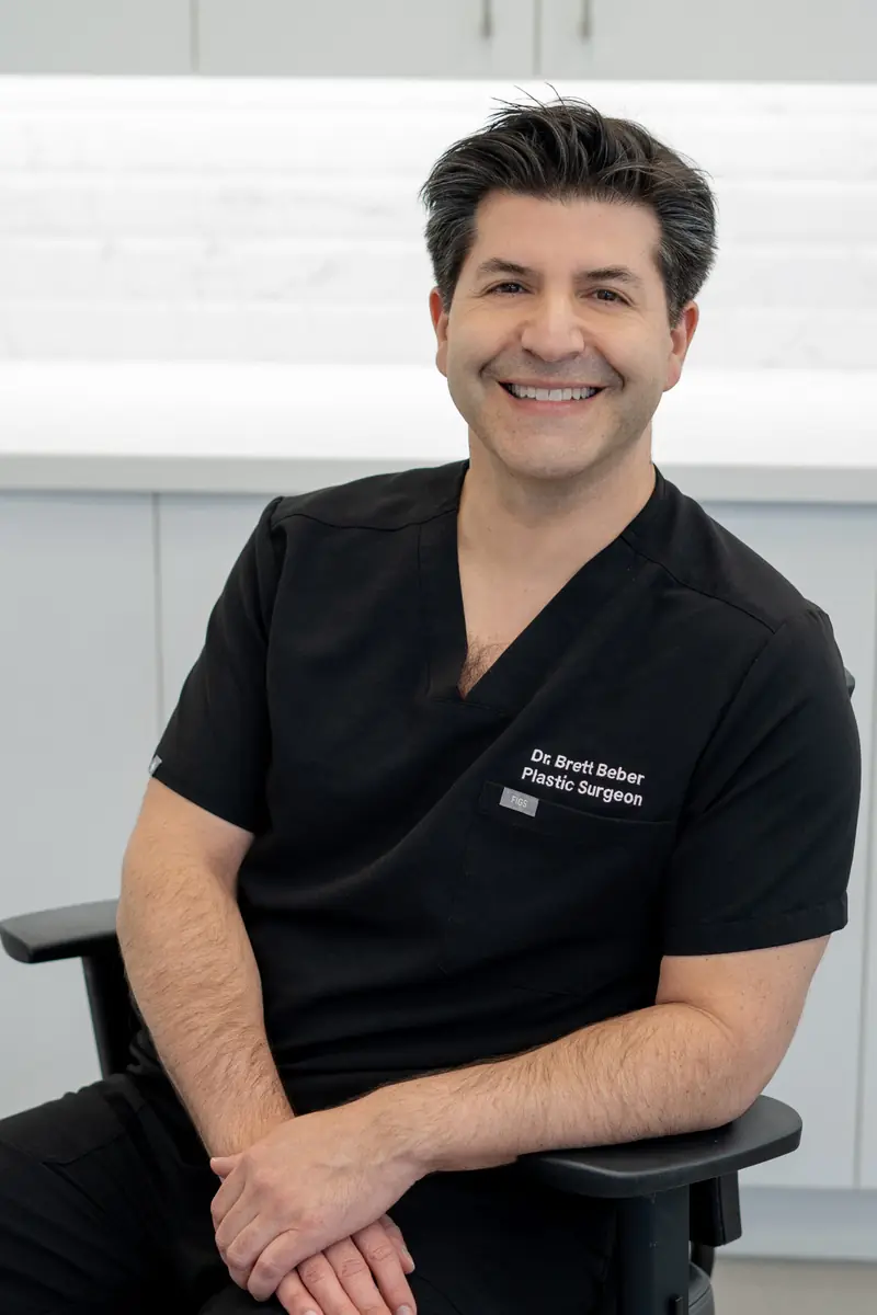Dr. Brett Beber seated in surgical scrubs, smiling