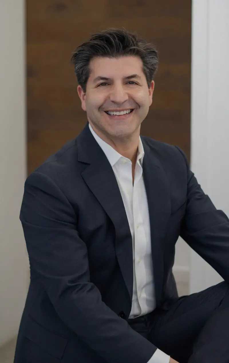 Dr. Brett Beber seated, in a navy suit