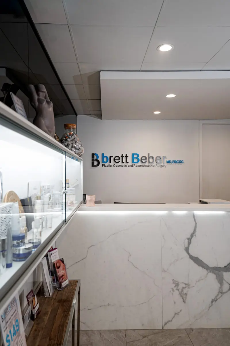 The reception at Beber Plastic Cosmetic Surgery, with its logo sign and marble counter